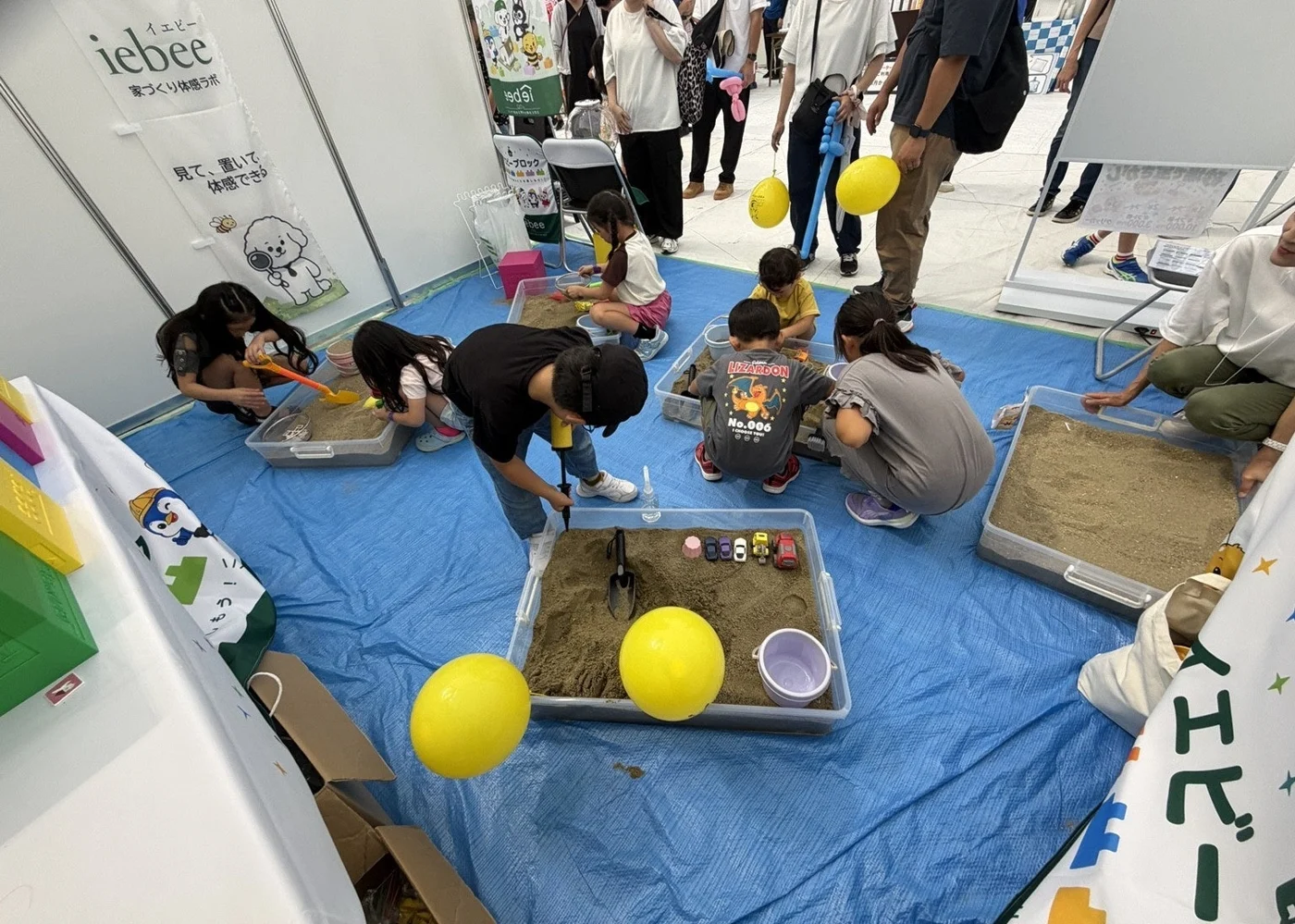 yabふれあいフェスタ2026で砂場を囲み、宝探しを楽しむ子どもたち